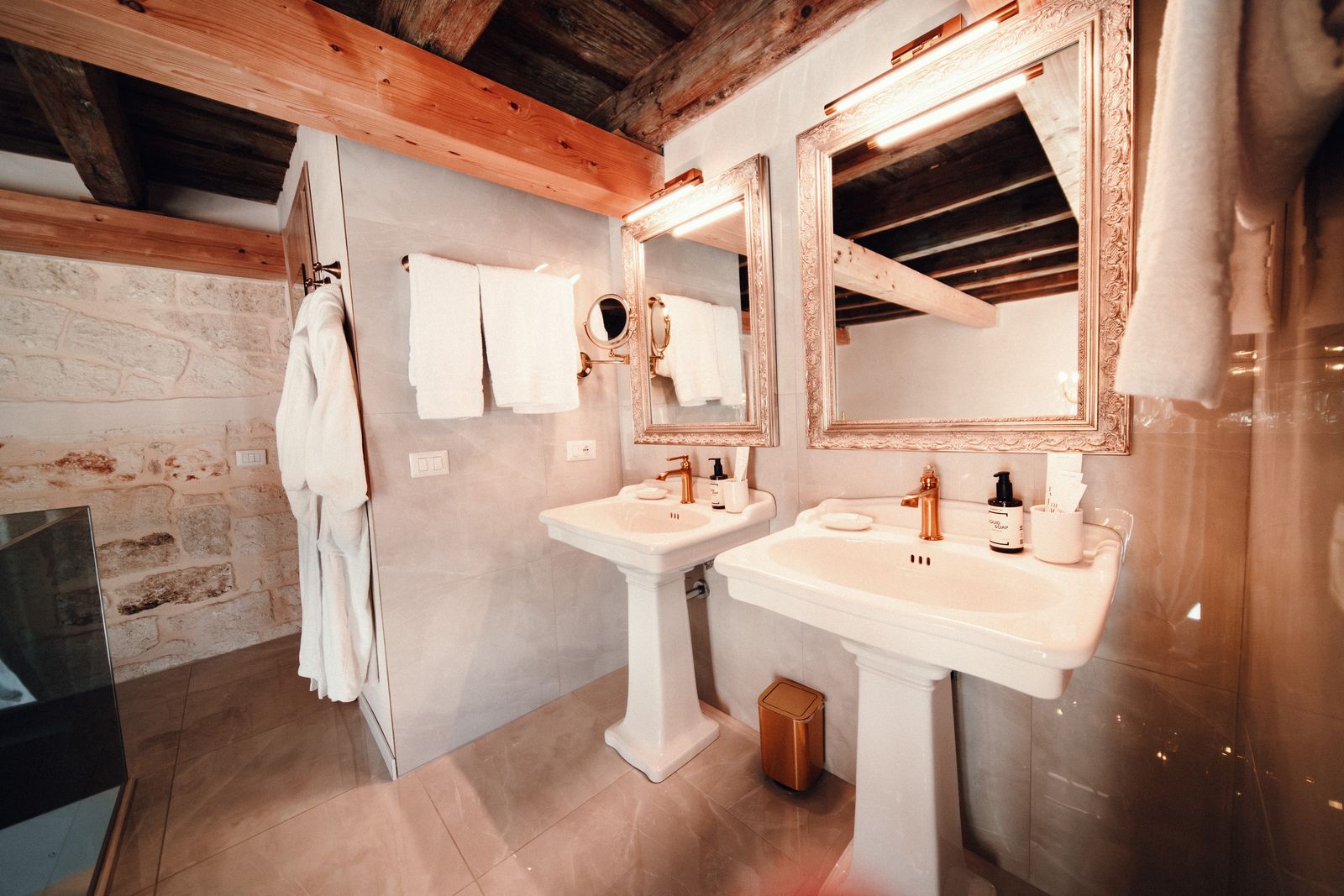 Two pedestal sinks and their ornate mirrors.