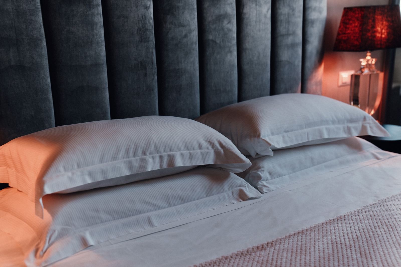 The grey velvet headboard and white pillows.
