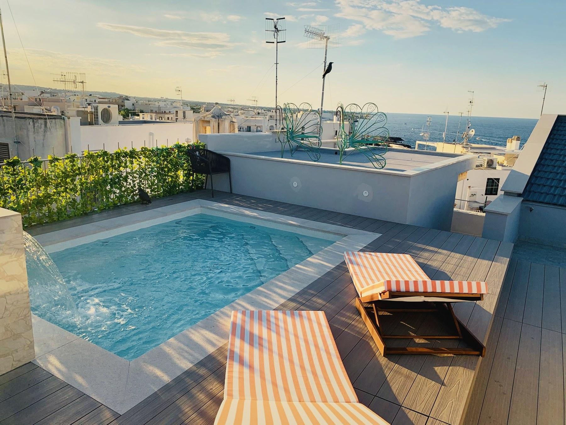The heated rooftop pool and its waterfall, with sun loungers on the deck and the Adriatic beyond the rooftops.